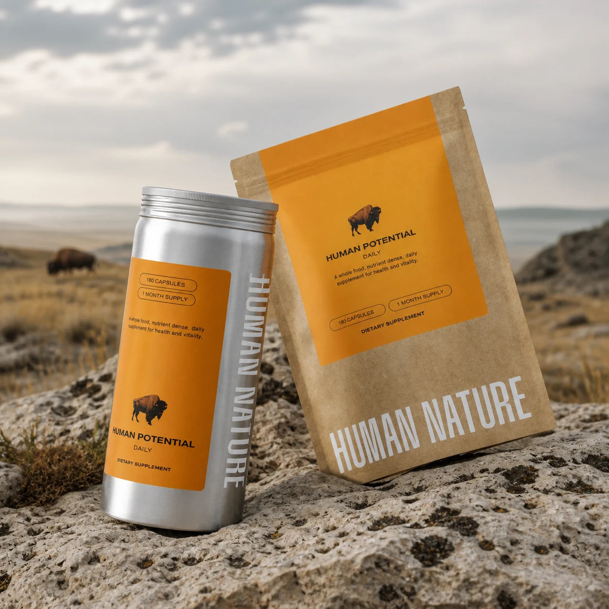 Human Potential's silver canister and orange refill pouch on prairie rock, with bison in the distance.